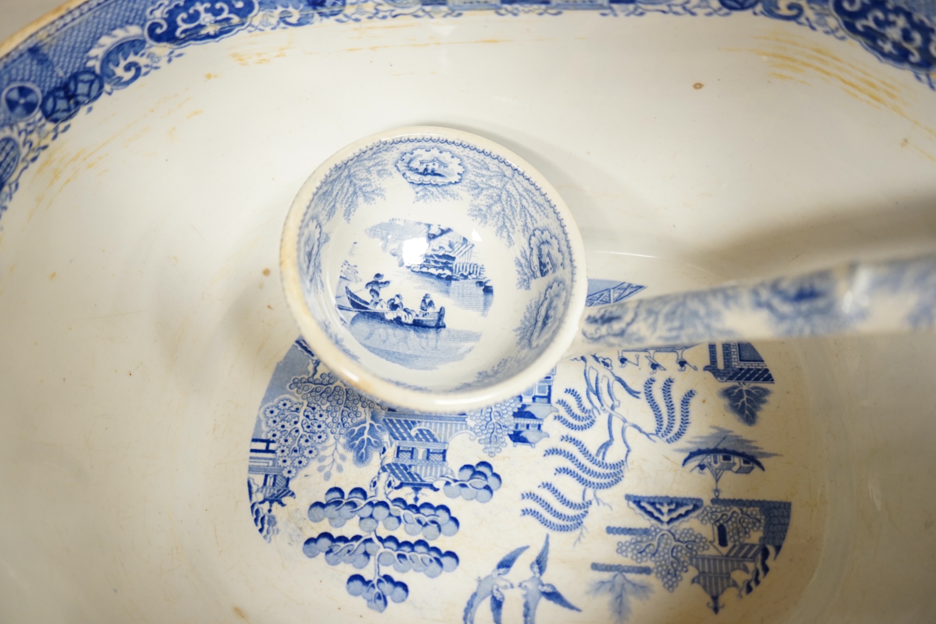 A large early to mid 19th century Pearlware meat platter and tureen without cover decorated with the ‘doctor calling’ pattern with a blue and white tureen cover and ladle, meat platter 54cm wide (3). Condition - fair